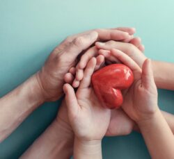Family holding hands with their child with a heart in their hands.