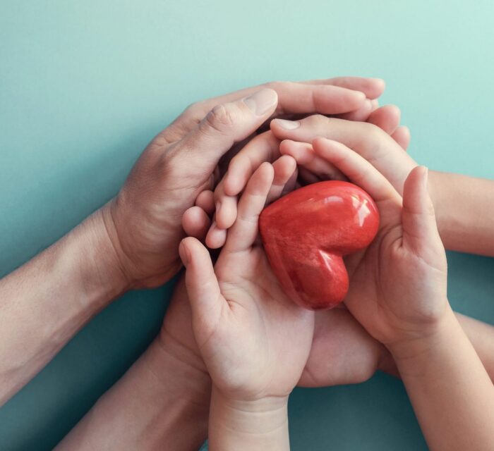 Family holding hands with their child with a heart in their hands.