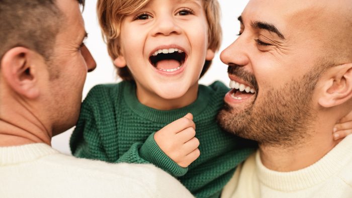 Same sex male couple smiling with their baby boy