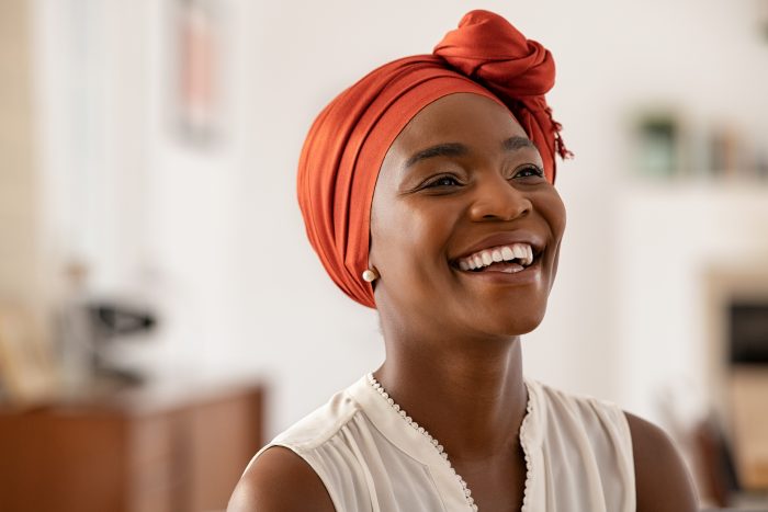 Smiling middle aged African American woman with orange headscarf on.