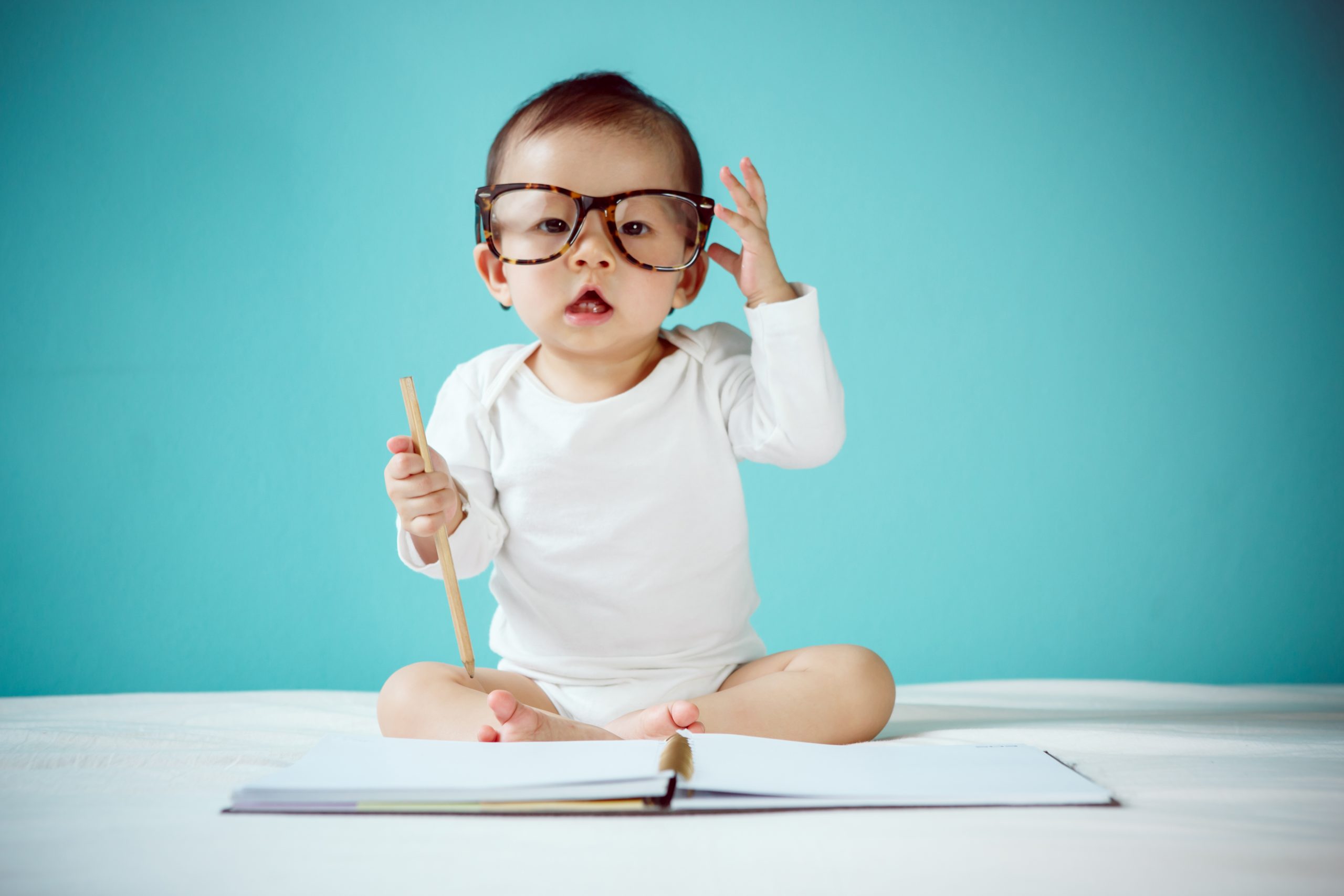 Baby with Parents Glasses on Writing in a Book