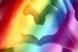 Touching hands in the shape of a heart and a rainbow overlay.