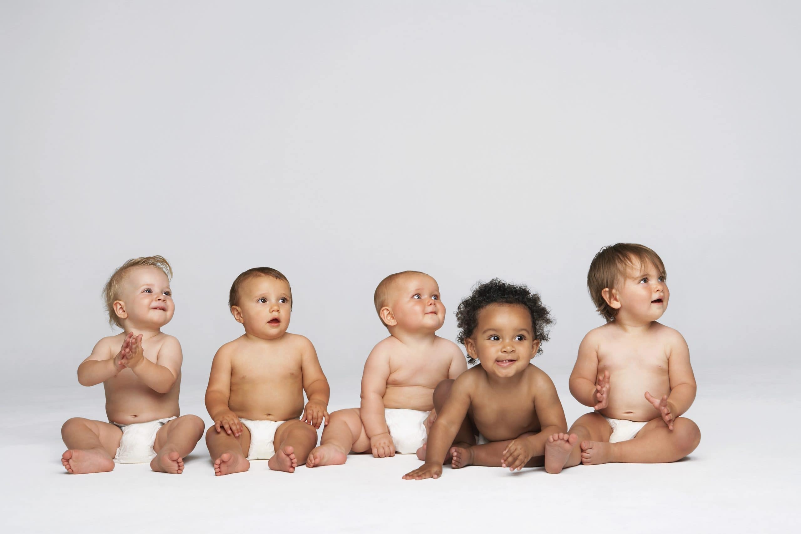 Group of mixed heritage babies sat down smiling.