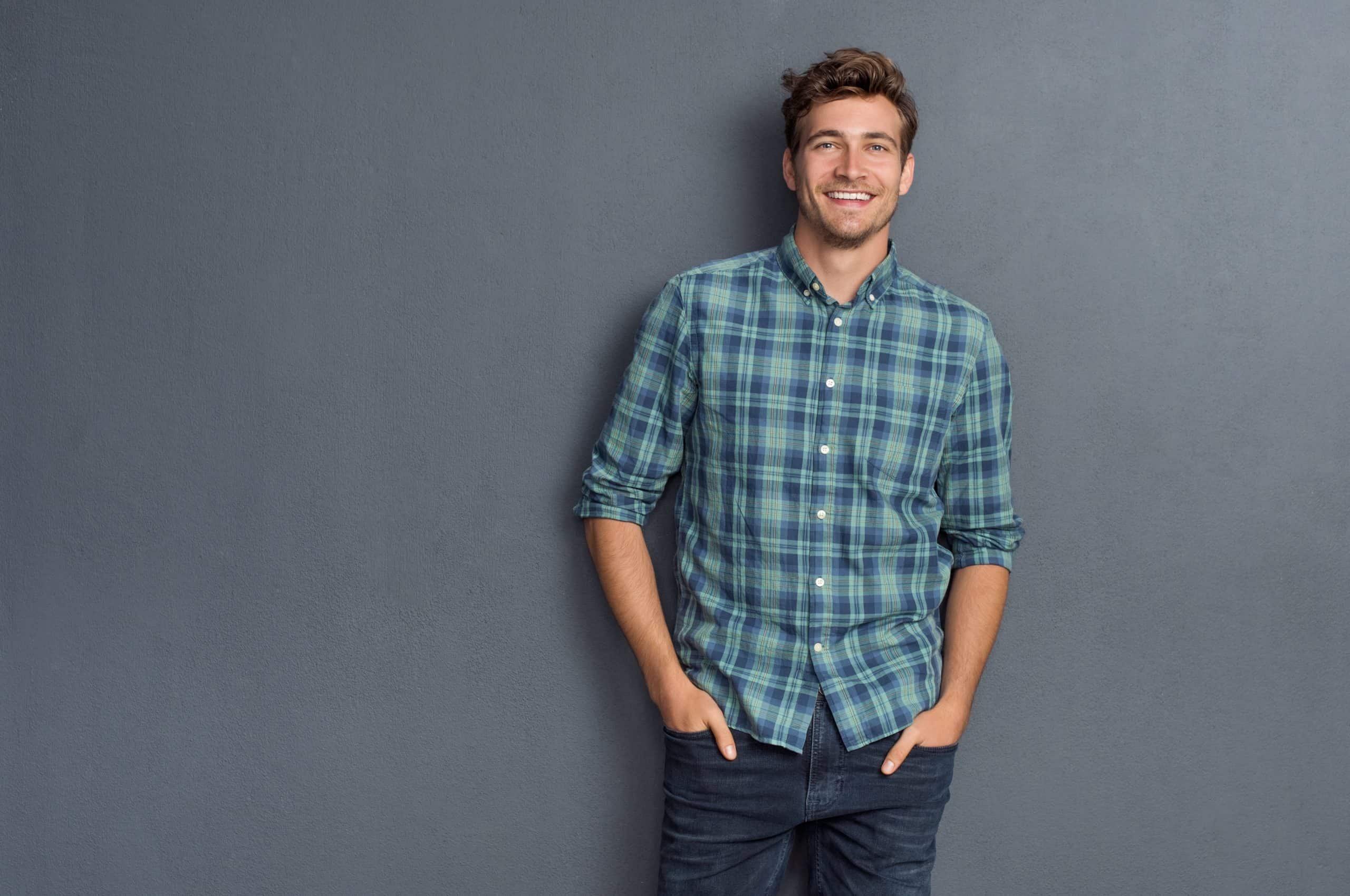 Wide shot of a man wearing a checkered shirt and smiling.