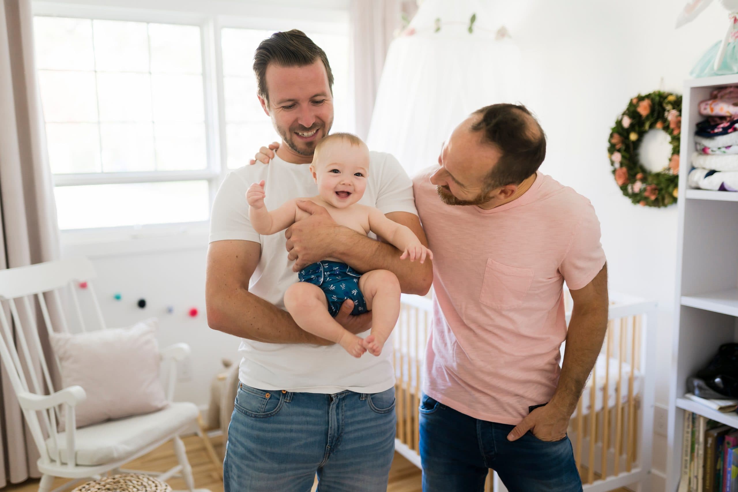 A same sex male couple enjoying holding their baby.